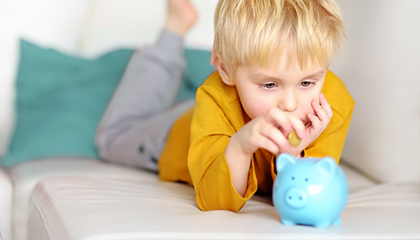 A young boy puts a coin in his piggy bank.